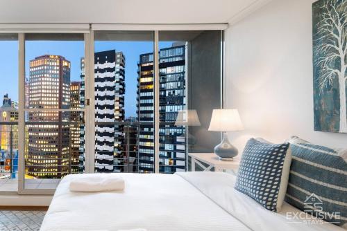 een slaapkamer met een wit bed en een groot raam bij Exclusive Stays - Boulevard Penthouse in Melbourne