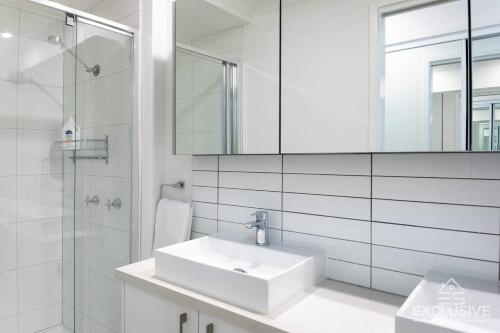een witte badkamer met een wastafel en een douche bij Exclusive Stays - Boulevard Penthouse in Melbourne