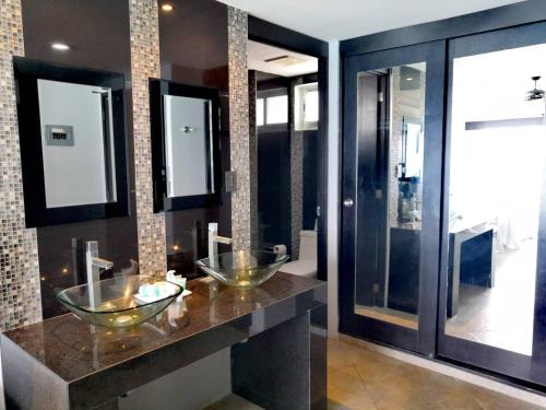 ein Badezimmer mit zwei Waschbecken auf einer Theke mit Spiegeln in der Unterkunft Cancun, Ocean Dream, Beautiful Aparment, Heart of the Hotel Zone in Cancún