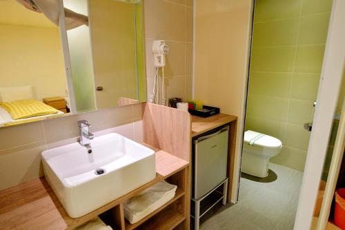 W łazience znajduje się umywalka, lustro i toaleta. w obiekcie Chengching Lakefront Resort w mieście Kaohsiung
