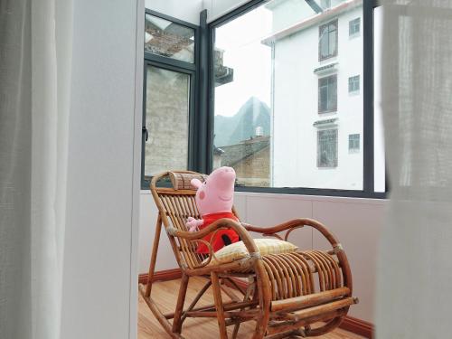 a stuffed animal sitting in a rocking chair in front of a window at Xingping Our Inn in Yangshuo