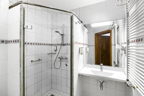 a white bathroom with a shower and a sink at Hotel Olympic in Wronki