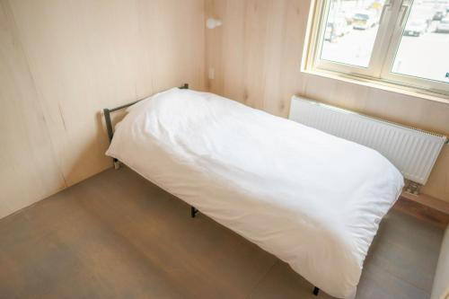 a bed with a white blanket in a room with a window at BEACH AND FIELD INN in Sapporo