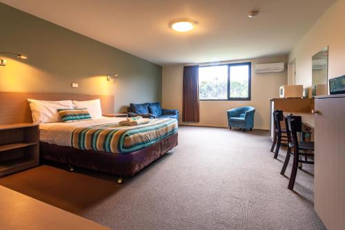 キングストンにあるKingston hotel Motelのベッド、デスク、椅子が備わるホテルルームです。