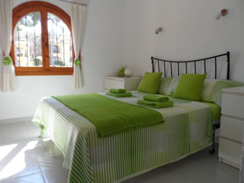 ein grünes und weißes Bett in einem weißen Schlafzimmer in der Unterkunft Brijon apartment in Moraira