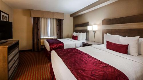a hotel room with two beds and a flat screen tv at Best Western Plus Executive Suites Albuquerque in Albuquerque