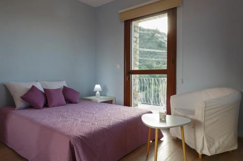 a bedroom with a purple bed and a chair and a window at LuimarVenue in Pano Lefkara