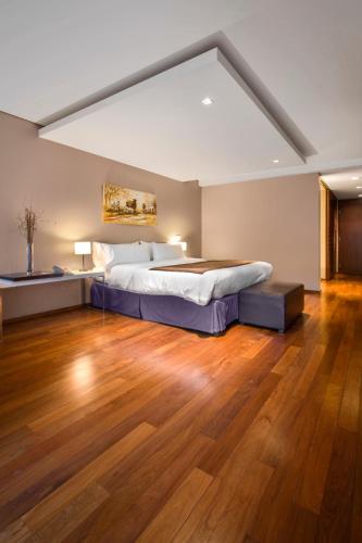 a large bedroom with a bed and a wooden floor at San Isidro Plaza Hotel in San Isidro