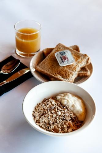 een kom granola en toast met een glas sinaasappelsap bij Silver Hills Motel in Queenstown