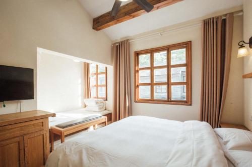 南京市にあるLao men dong International Youth Hostelの白いベッドとテレビのある寝室