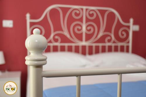 a bedroom with a white bed with a red wall at Hotel Ascot in Caianello