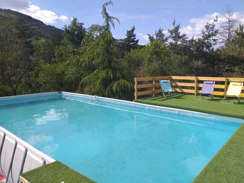 - une piscine avec 2 chaises et un banc dans l'établissement Un petit coin de paradis, à Gluiras