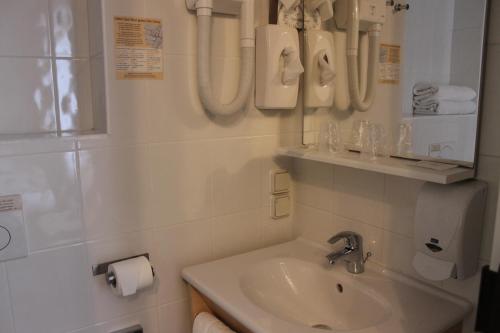 een witte badkamer met een wastafel en een spiegel bij Hotel De La Mer in Quiberon