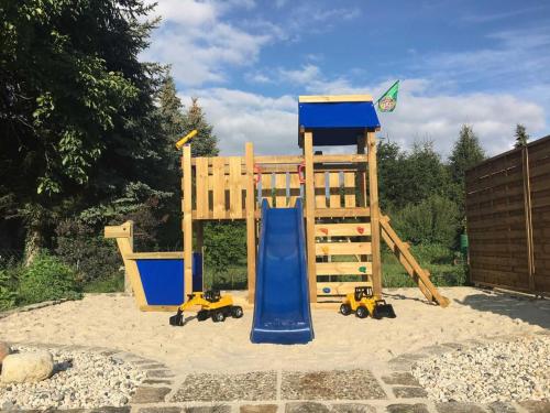 a playground with a slide and playset in the sand at Ferienhaus _GlueckSEEligkeit_ in Großkoschen