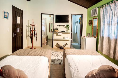 um quarto com duas camas e uma televisão em Pousada e Restaurante Fim da Trilha na Ilha do Mel