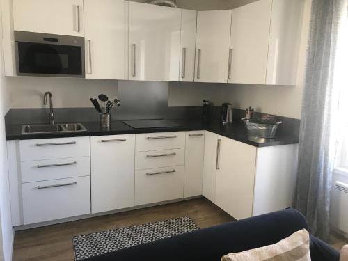 une cuisine avec des armoires blanches et un comptoir noir dans l'établissement Le Cocon d Agathe, à Grandcamp-Maisy