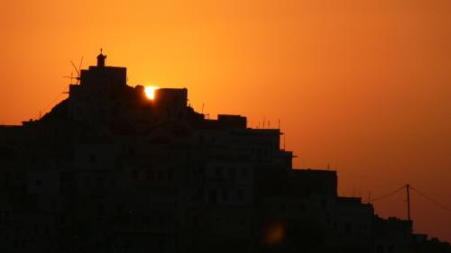 a silhouette of a building with the sun setting behind it at Roses Studios in Karpathos Town