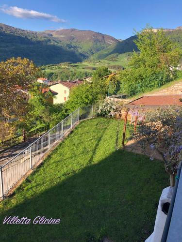 a view of a yard with a fence and mountains at Villetta Glicine in Brentonico