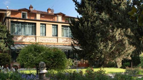 a building with a statue in front of a garden at Villa Belverde Boutique Hotel in Carrara