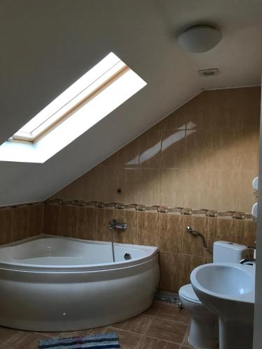 a bathroom with a tub and a sink and a skylight at Pensiunea Igazland *** in Dumbrava