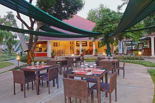 an outdoor dining area with tables and chairs and a building at Metland Hotel Cirebon in Cirebon