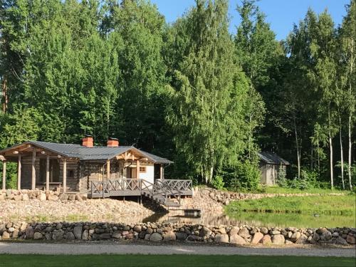 a log cabin by the water with a stone wall at Dzirnavas Pirtsmāja in Cesvaine
