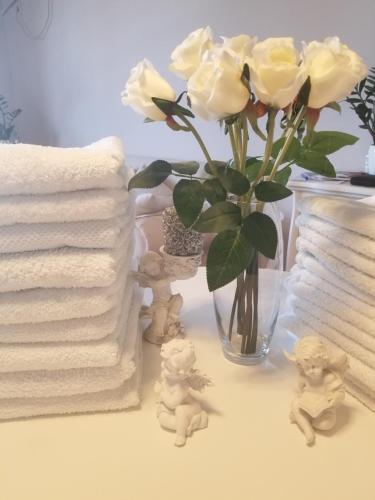 une table avec des roses blanches dans un vase et des serviettes dans l'établissement Stan na dan Angel, à Novi Sad