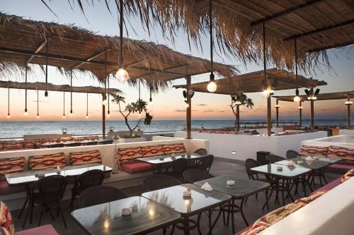 a restaurant on the beach with tables and chairs at La Siesta Hotel & Beach Resort in Khaldah