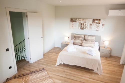 Schlafzimmer mit einem Bett mit weißer Bettwäsche und Kissen in der Unterkunft Can Cedre in Lliçà d'Amunt