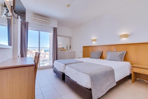 a hotel room with a bed and a balcony at Vila Recife Hotel in Albufeira