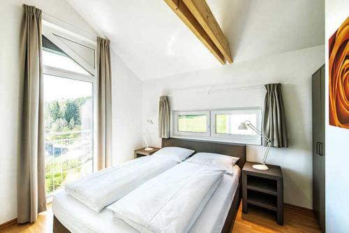 ein Schlafzimmer mit einem großen Bett und einem Fenster in der Unterkunft Einzelhaus Classic im Feriendorf an der Therme Obernsees in Truppach