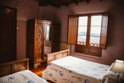 1 dormitorio con 2 camas y ventana en Carquera Casa a 8 Km de Nava, en Nava