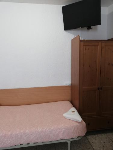 a room with a bed and a cabinet and a flat screen tv at Pensión Fortea in Zaragoza