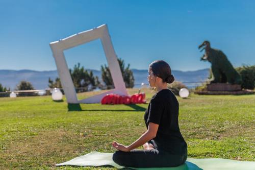 a woman sitting in a field doing a meditation at Augusta Eco Wellness Resort 4 Superior in Sanxenxo