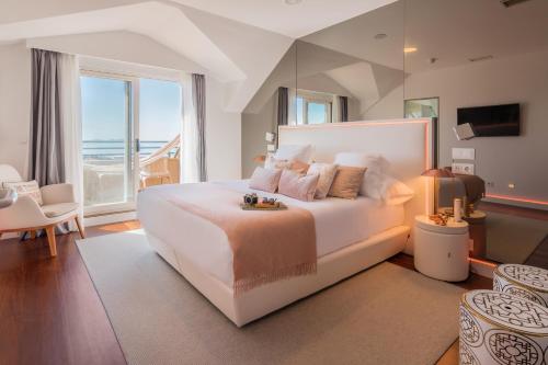 1 dormitorio con 1 cama blanca grande y vistas al océano en Augusta Eco Wellness Resort 4 Superior, en Sanxenxo