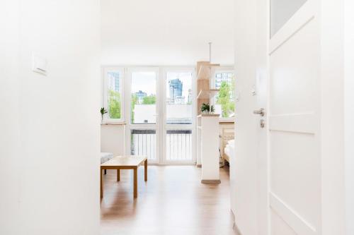 Biały salon z drzwiami i stołem w obiekcie Apartments Warsaw Pereca by Noclegi Renters w Warszawie