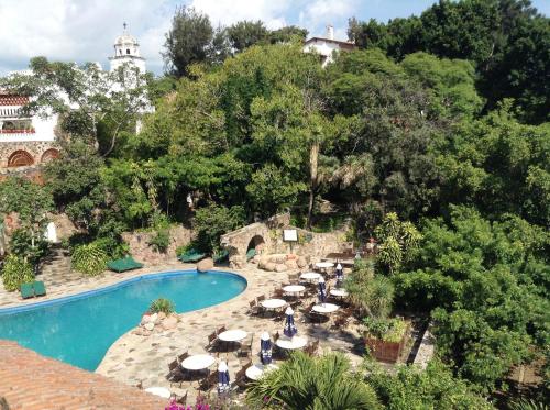 a pool with umbrellas and chairs next to a resort at Posada de la Mision, Hotel Museo y Jardin in Taxco de Alarcón