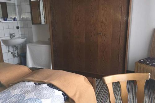 ein Badezimmer mit einem Waschbecken, einem Bett und einem Stuhl in der Unterkunft Ferienwohnung Schwalbenwandblick in Saalfelden am Steinernen Meer