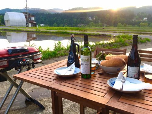 a wooden picnic table with bottles of wine and bread at KOME HOME in Tokamachi