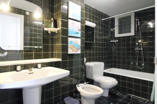 セグル・デ・カラフェルにあるApartamento Playa Doradaの黒いタイル張りのバスルーム(洗面台、トイレ付)