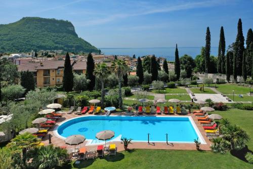 Blick auf den Pool in einem Resort mit Stühlen und Sonnenschirmen in der Unterkunft Villa Madrina Lovely and Dynamic Hotel in Garda