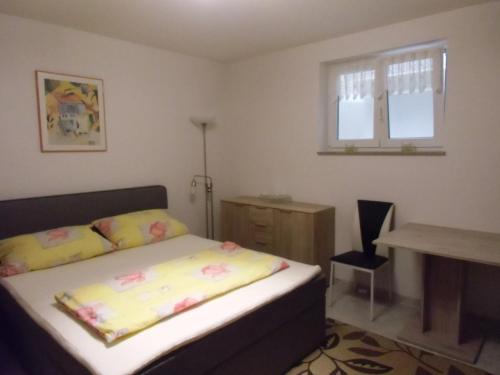 a bedroom with a bed and a desk and a window at Ferienwohnung Keil in Lahr