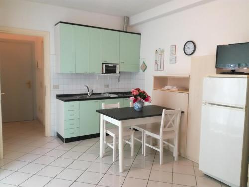 a kitchen with green cabinets and a table with chairs at Residence Marina in Alassio