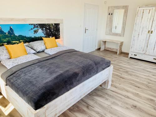 a bedroom with a large wooden bed with yellow pillows at Penzion Holín u Prachovských skal in Jičín