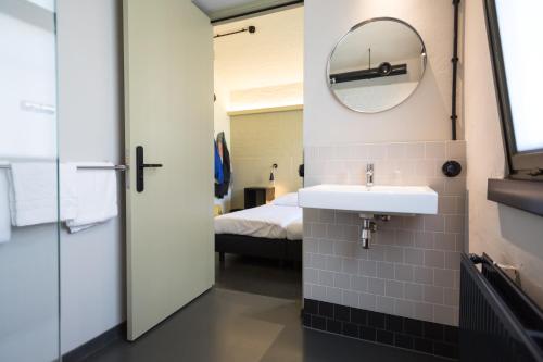 een badkamer met een wastafel en een bed bij Alibi Hostel Leeuwarden in Leeuwarden