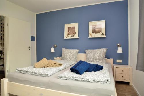 Ferienwohnung Küstenwaldblick mit privat Sauna, 87qm & 2 Schlafzimmern في غرال موريتز: سريرين في غرفة نوم بجدران زرقاء