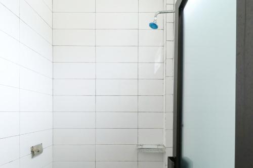 ducha con pared de azulejos blancos en Riviera Residence, en Balikpapan