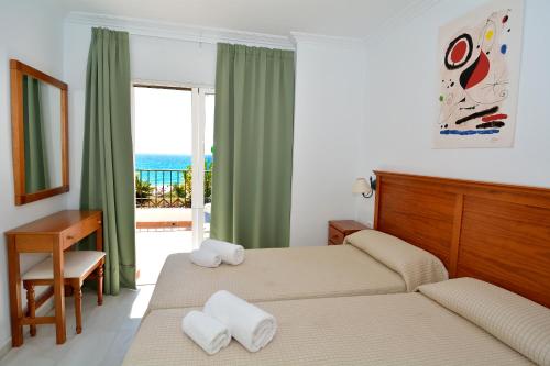 a bedroom with two beds and a balcony with the ocean at Apartamentos HC Burriana Playa in Nerja