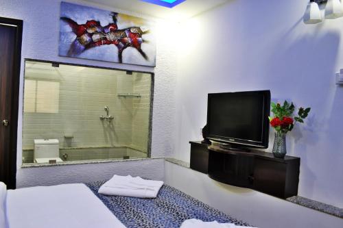 Zimmer mit einem TV und einem Bett sowie einem Bad. in der Unterkunft Fusion Resorts in Candolim
