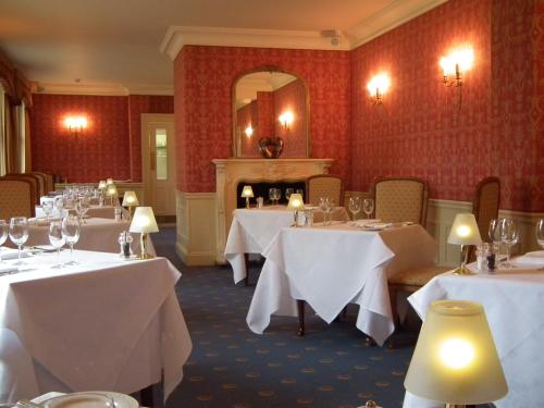 a dining room with white tables and a fireplace at Esseborne Manor in Hurstbourne Tarrant